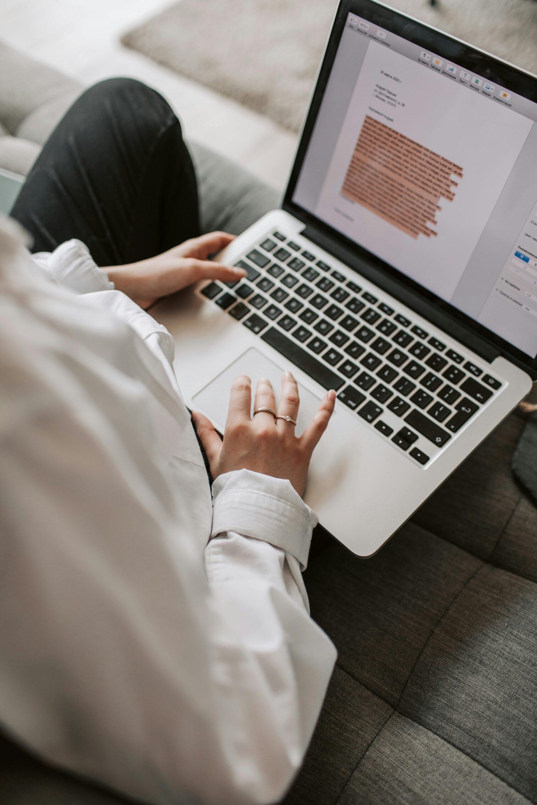 Programas Woman working on a laptop indoors, focusing on document editing and remote work.
